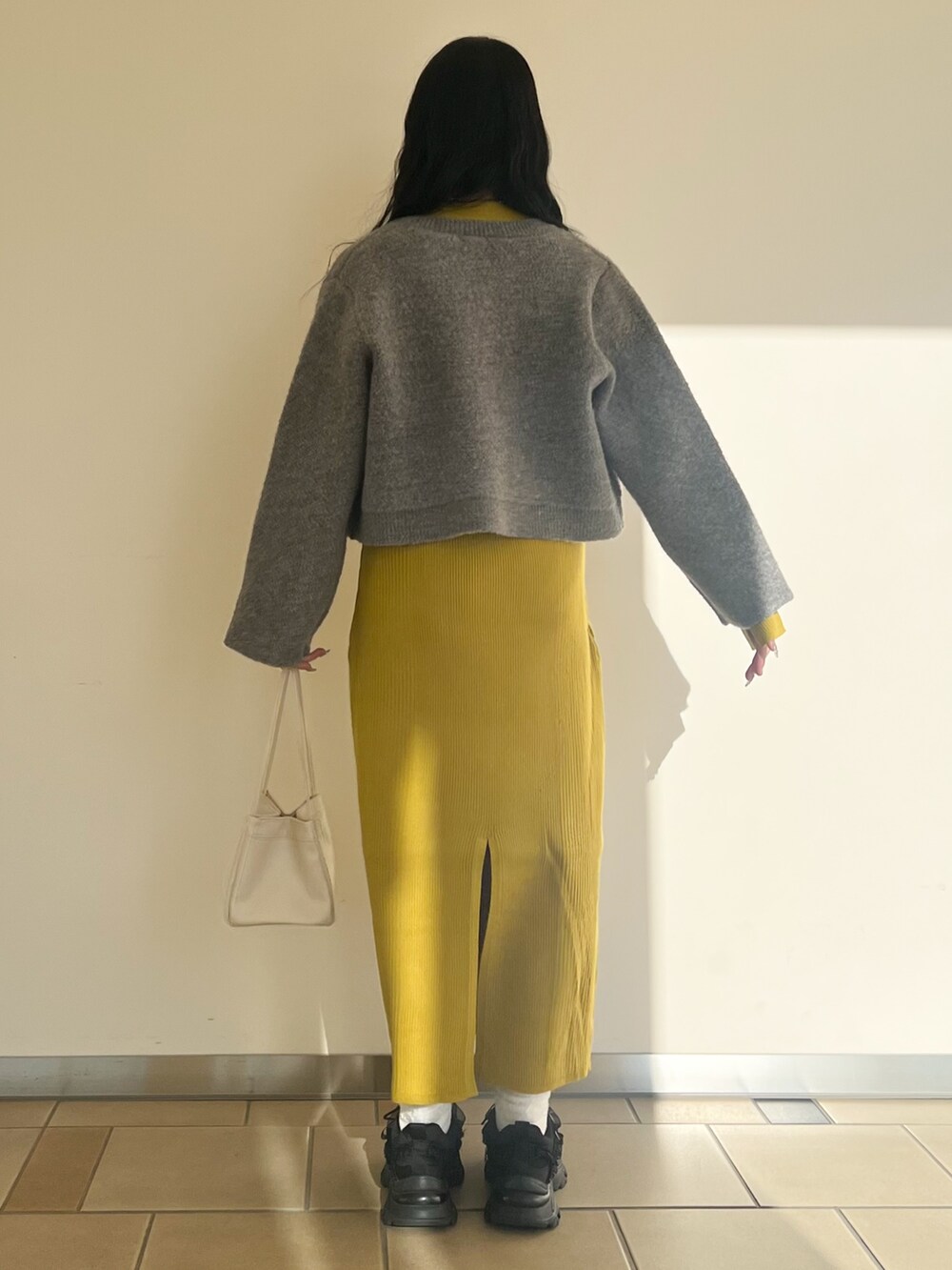 イエロー系のワンピース、グレー系のカーディガン/ボレロを着用したレディースの冬コーディネートの2枚目の写真