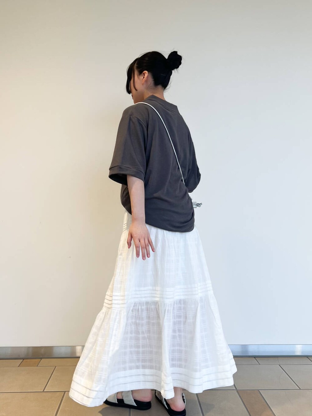 グレー系のサンダル、シルバー系のショルダーバッグ、ホワイト系のスカートを着用したレディースの夏コーディネートの2枚目の写真