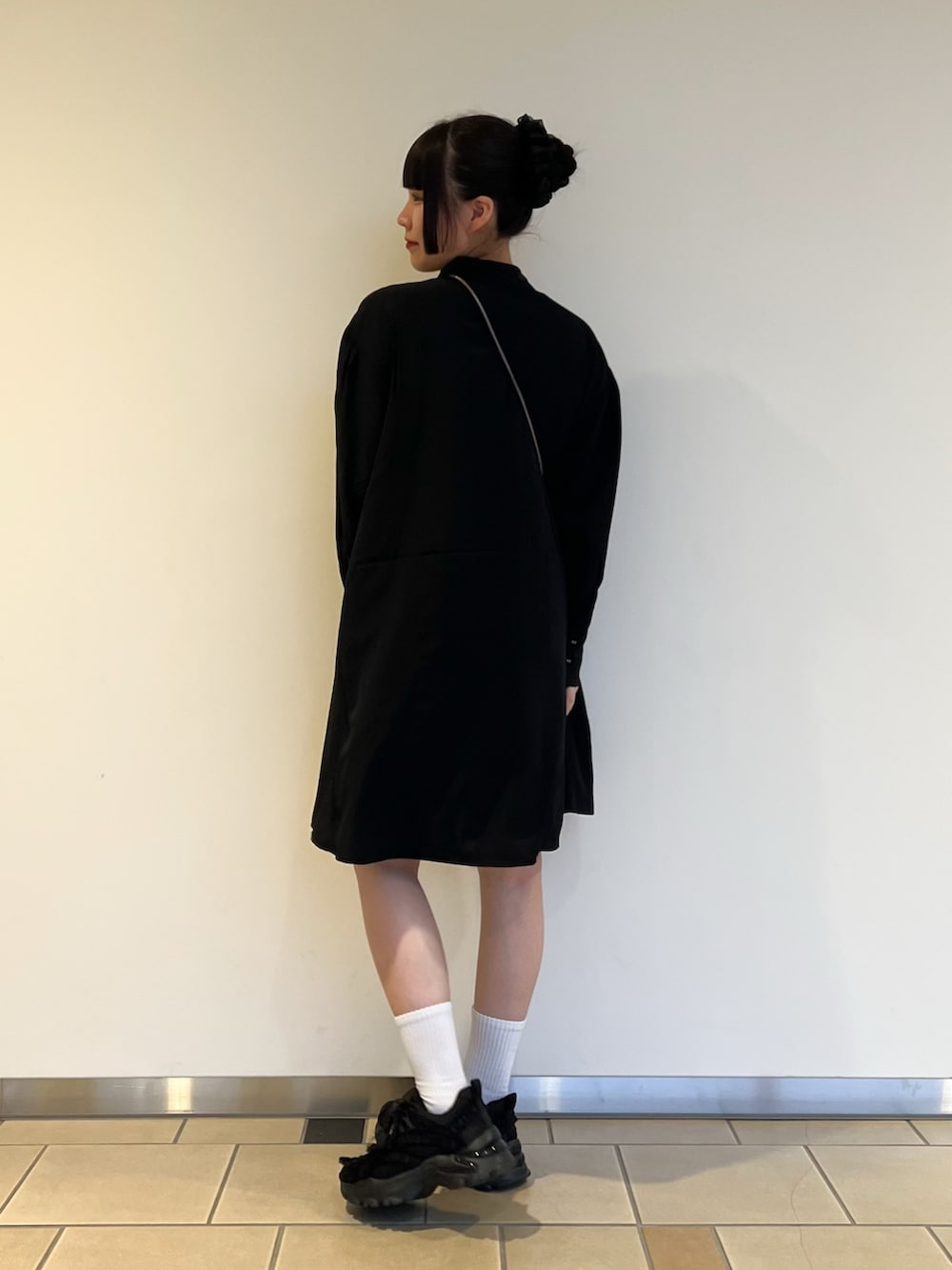 ブラック系のチュニック、シルバー系のショルダーバッグを着用したレディースの秋コーディネートの2枚目の写真