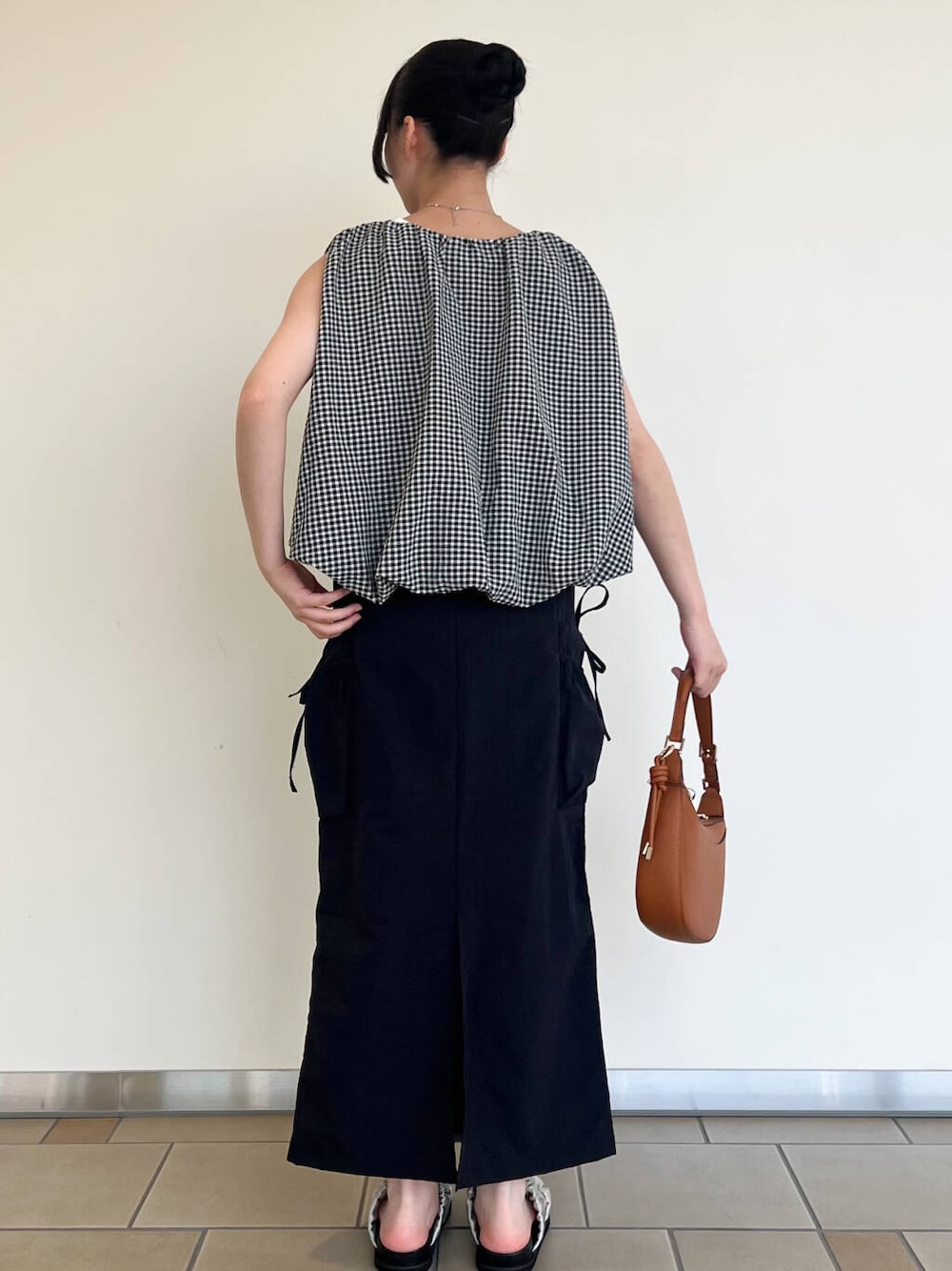 グレー系のサンダル、ブラック系のスカート、ホワイト系のシャツ/ブラウスを着用したレディースの夏コーディネートの3枚目の写真