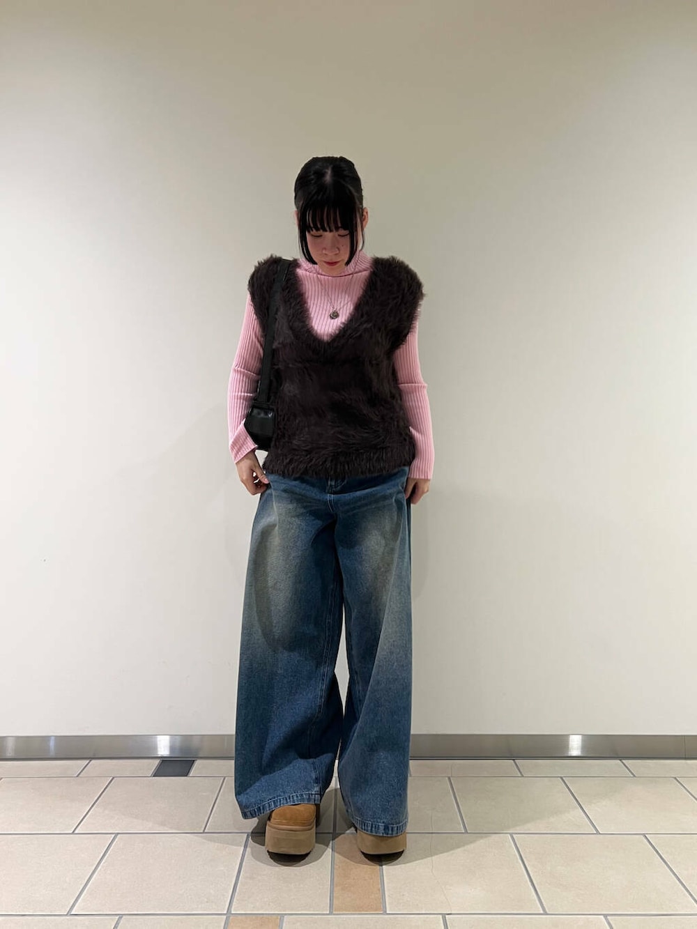 ピンク系のニット/セーター、ブラック系のハンドバッグ、ブルー系のデニムパンツを着用したレディースの冬コーディネートの2枚目の写真