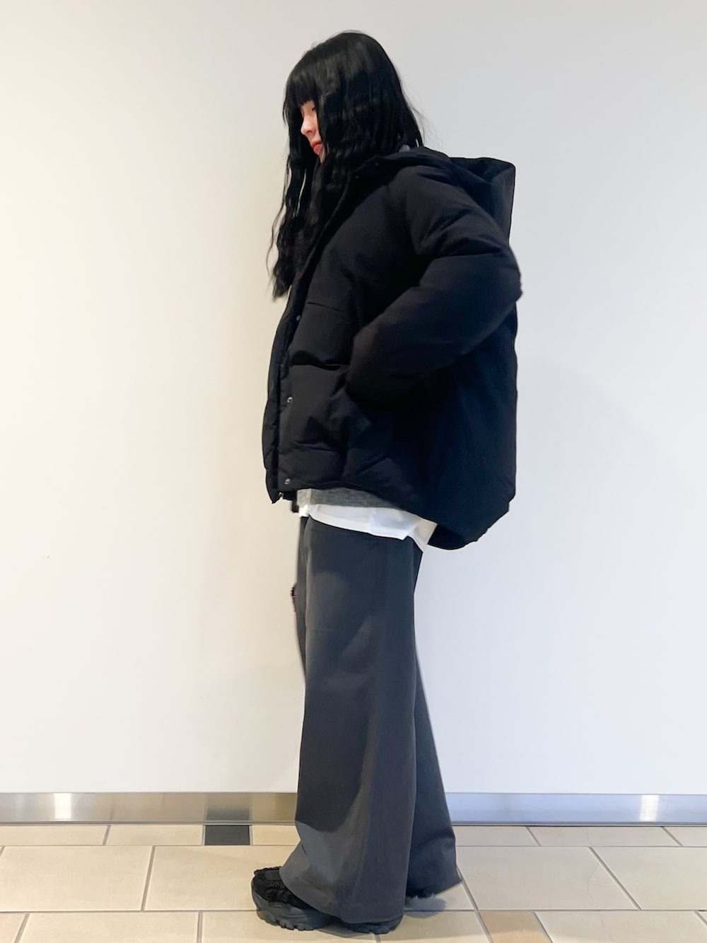 ホワイト系のTシャツ/カットソー、グレー系のニット/セーター、ブラック系のダウンジャケット/コートを着用したレディースの冬コーディネートの3枚目の写真