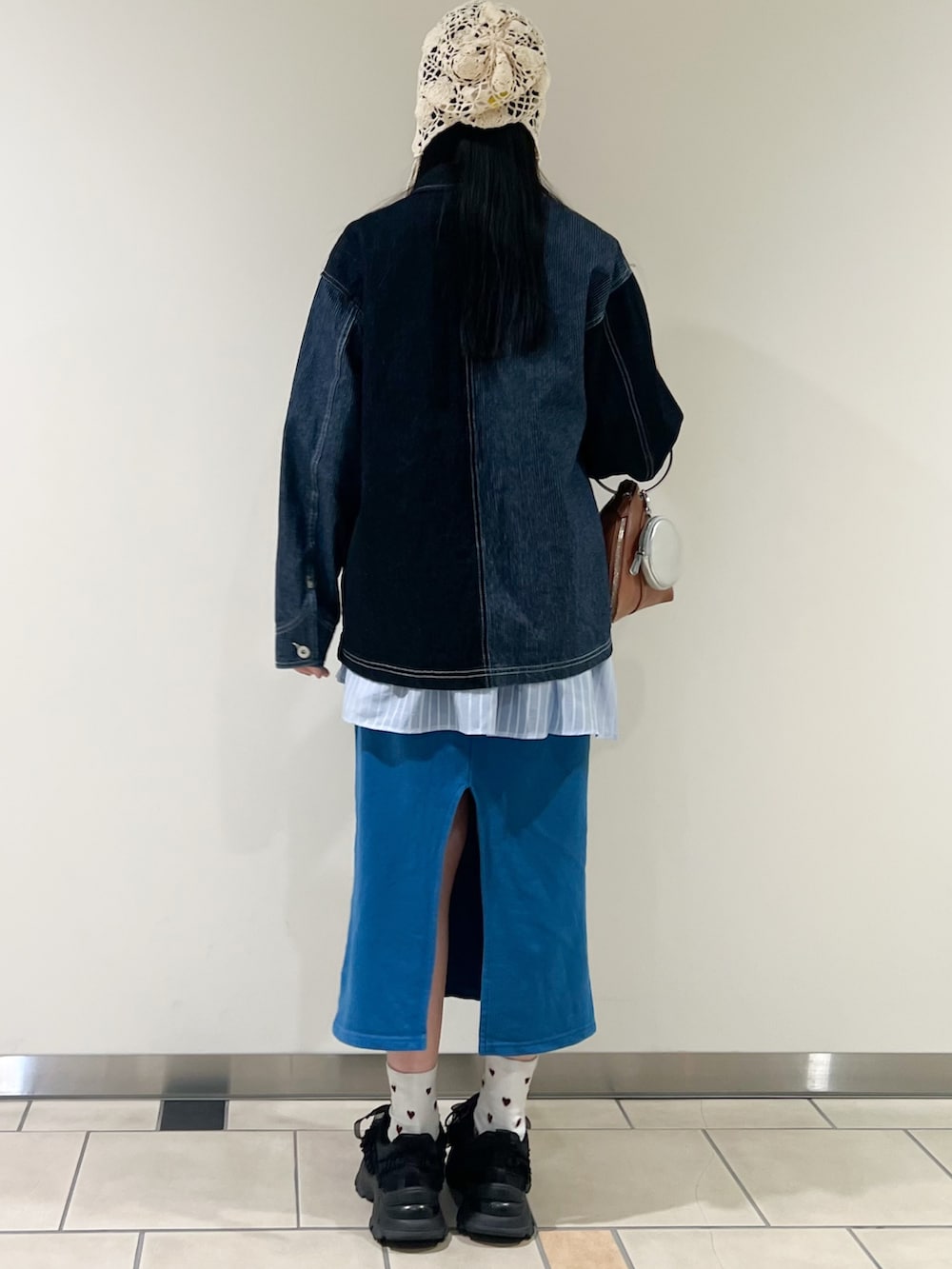 ブルー系のデニムジャケット、ブルー系のワンピース、イエロー系のハンドバッグを着用したレディースの春コーディネートの2枚目の写真