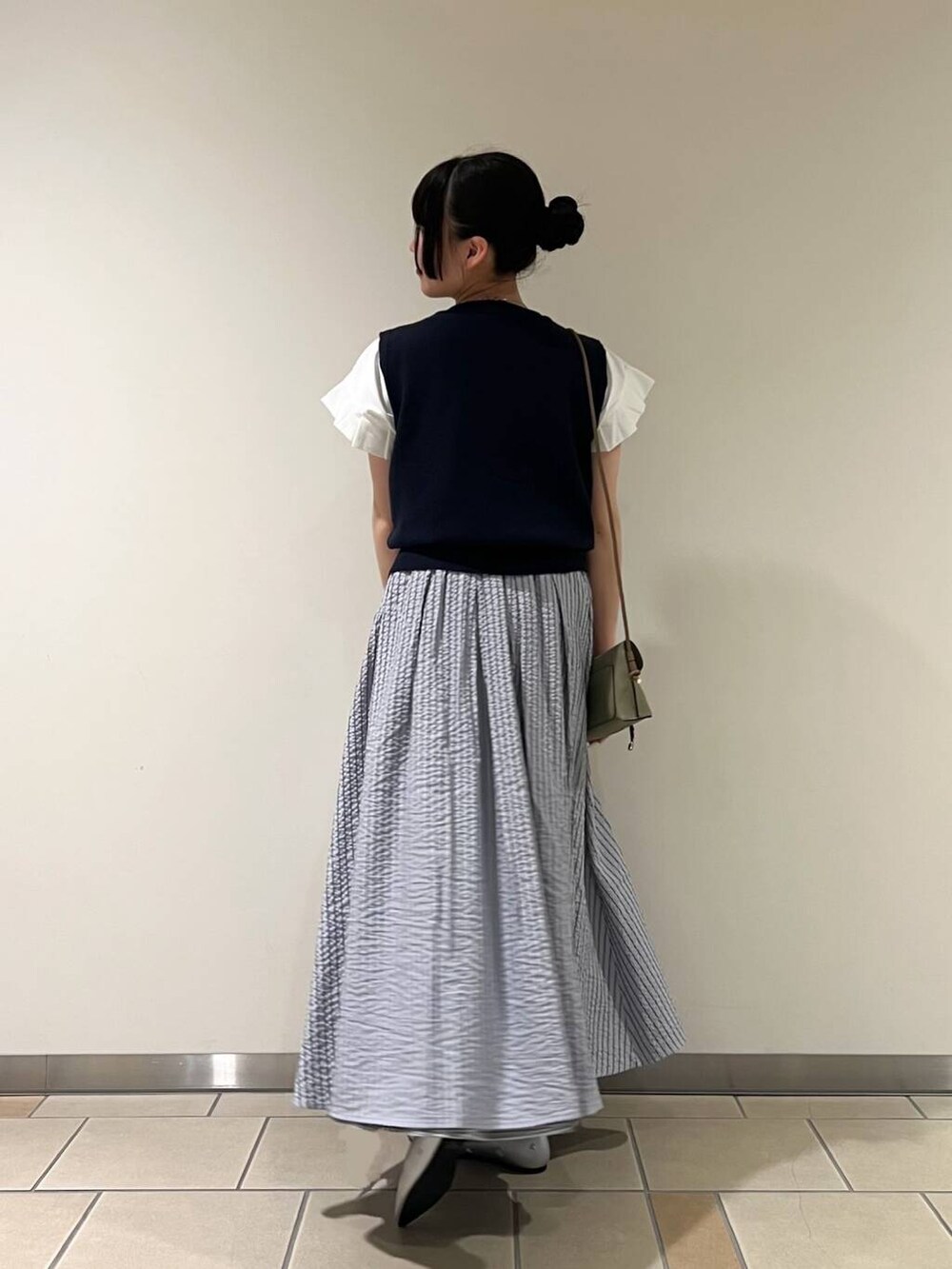 シルバー系のパンプス、グリーン系のショルダーバッグ、ホワイト系のTシャツ/カットソーを着用したレディースの夏コーディネートの2枚目の写真