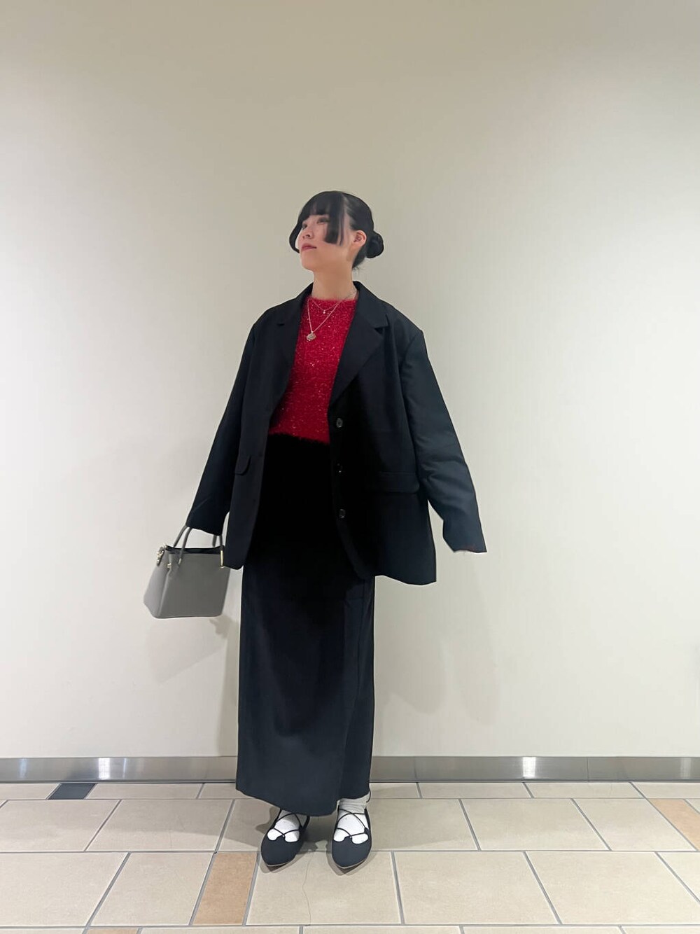 グレー系のトートバッグ、ブラック系のスカート、ブラック系のテーラードジャケットを着用したレディースの冬コーディネートの3枚目の写真