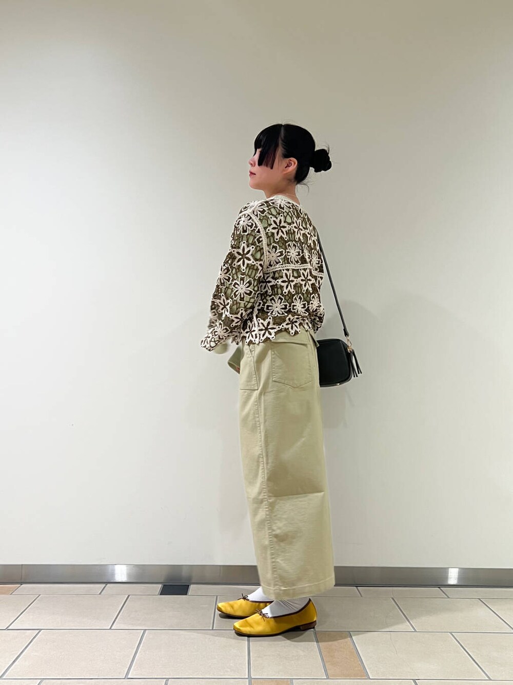イエロー系のバレエシューズ、グリーン系のショルダーバッグ、グリーン系のTシャツ/カットソーを着用したレディースの冬コーディネートの2枚目の写真