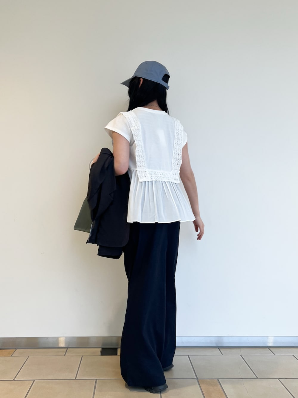 ホワイト系のTシャツ/カットソー、グレー系のダウンベスト、ブルー系のその他パンツを着用したレディースの春コーディネートの4枚目の写真