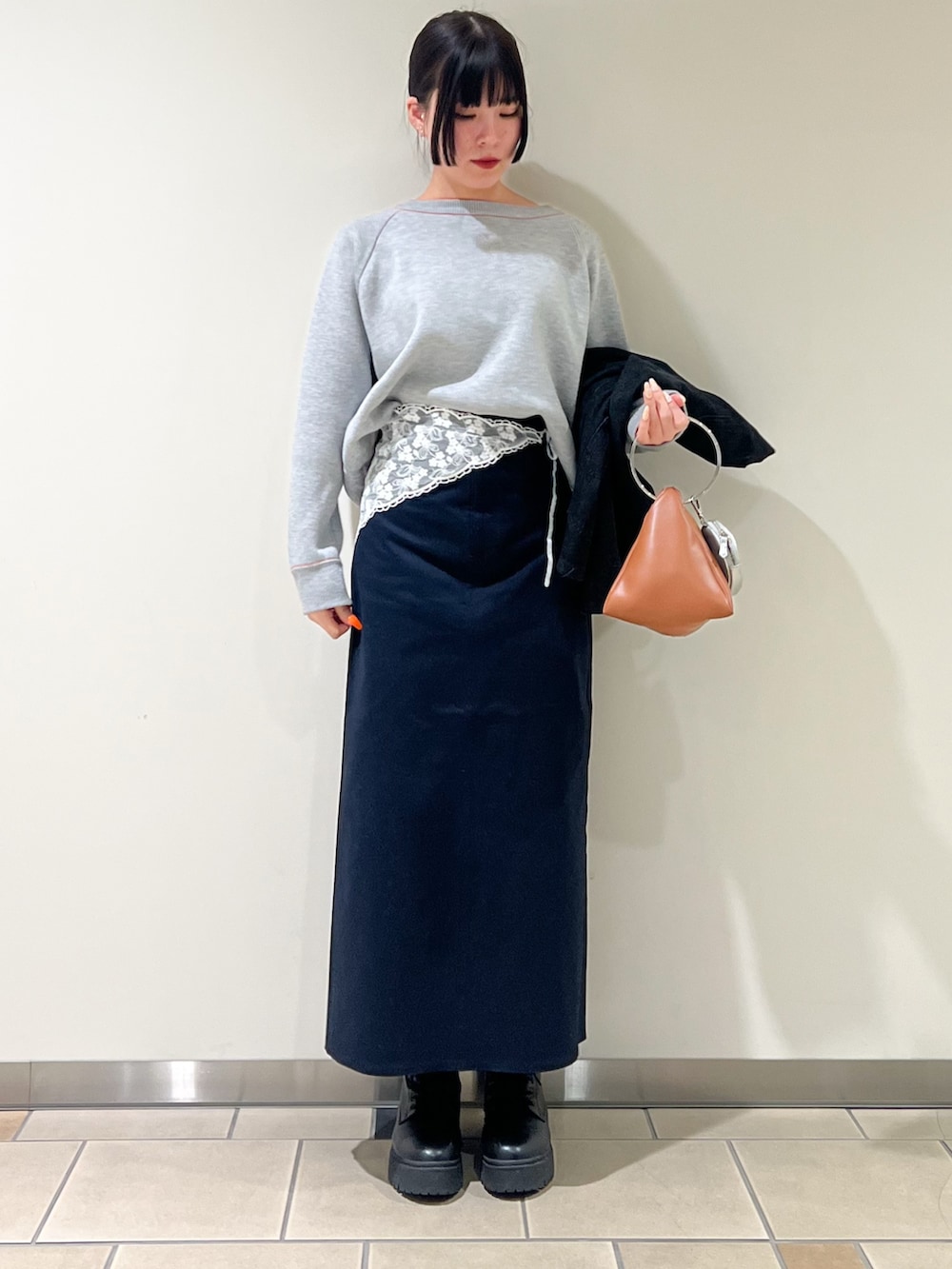 オレンジ系のニット/セーター、ブラック系のデニムジャケット、ブルー系のスカートを着用したレディースの冬コーディネートの4枚目の写真