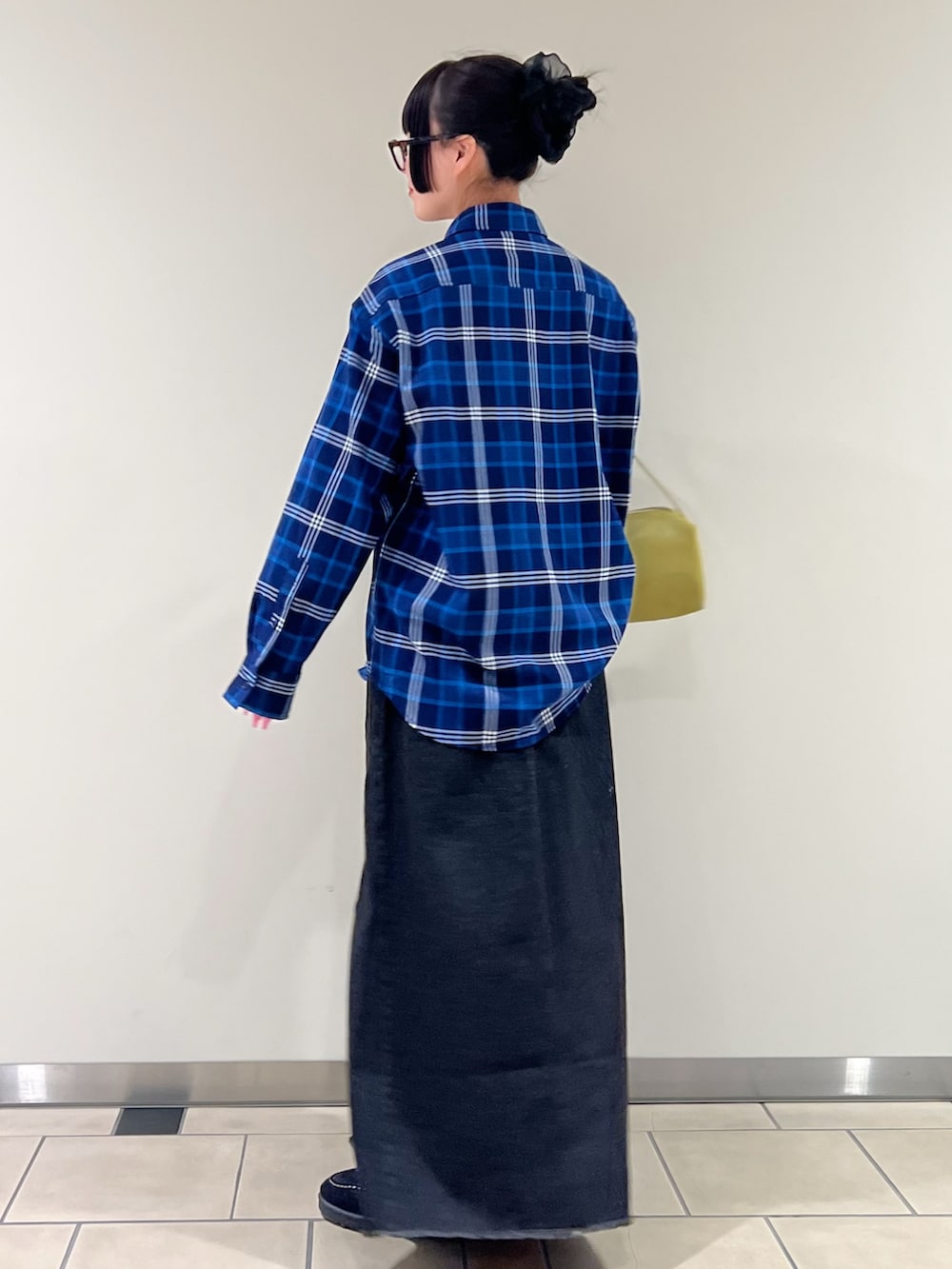 ブルー系のシャツ/ブラウス、ブラック系のスカート、イエロー系のトートバッグを着用したレディースの春コーディネートの2枚目の写真