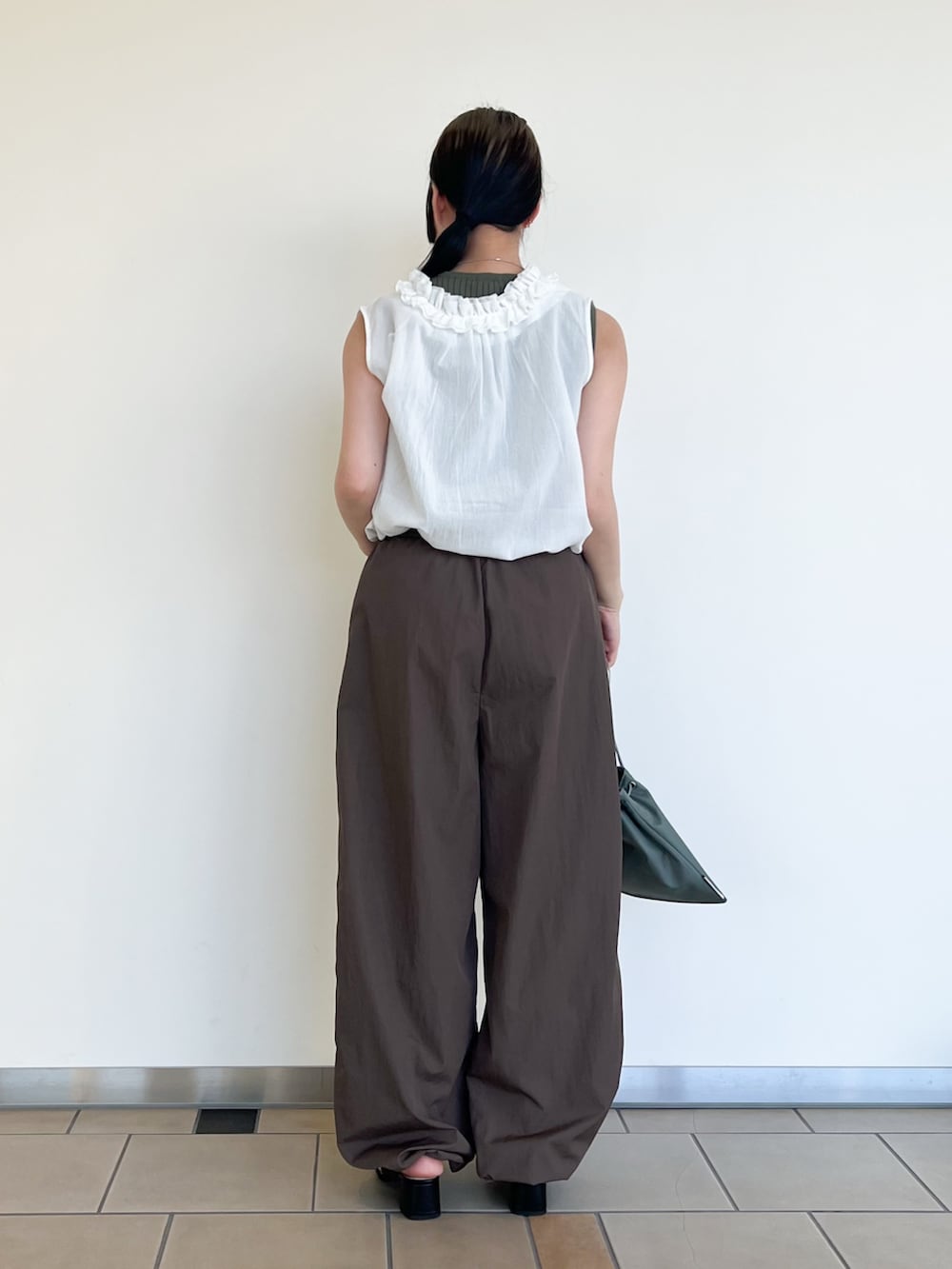 ブラウン系のその他パンツ、ホワイト系のシャツ/ブラウス、グリーン系のニット/セーターを着用したレディースの夏コーディネートの3枚目の写真