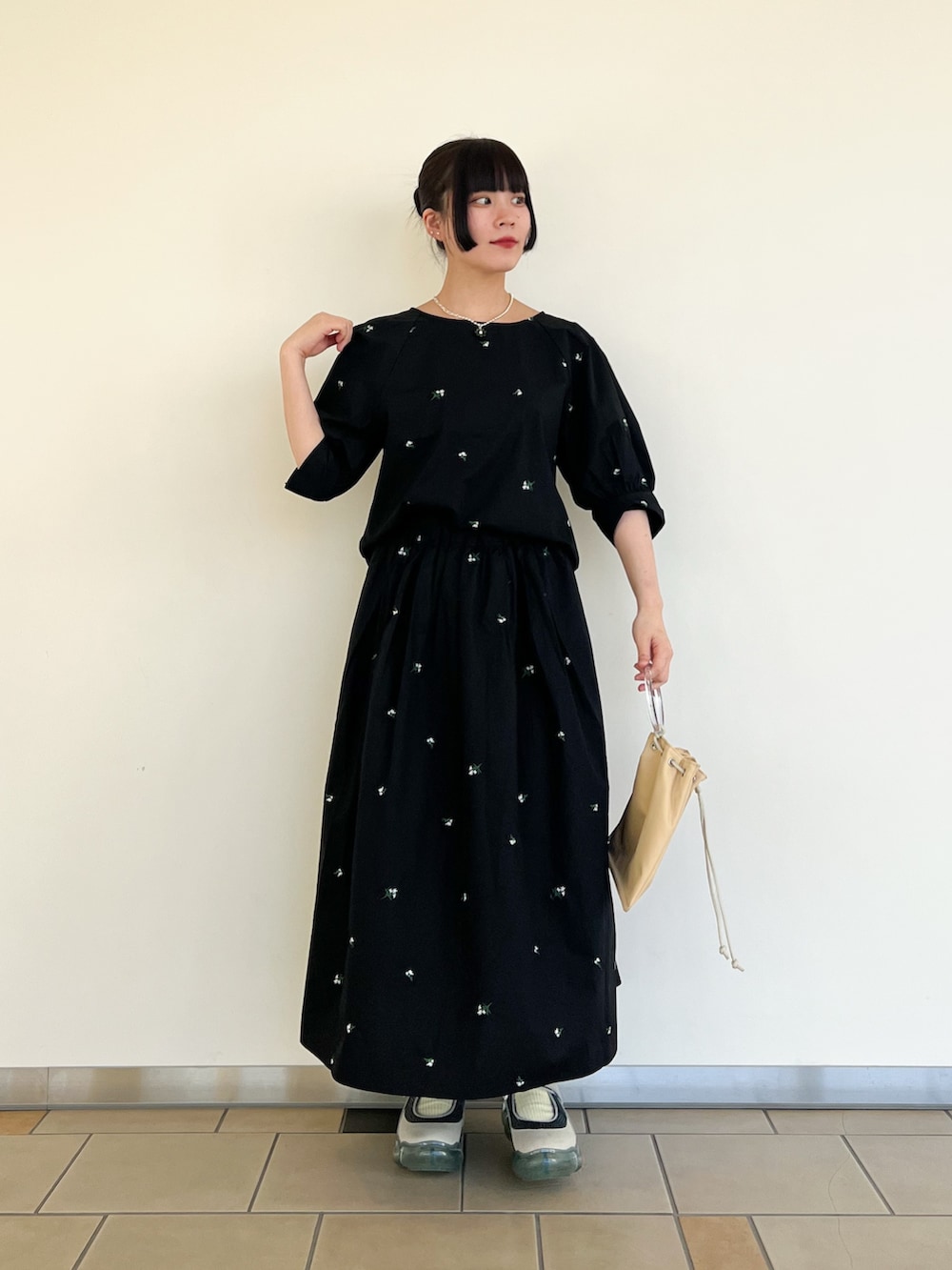 ブラック系のシャツ/ブラウス、ブラック系のスカート、イエロー系のショルダーバッグを着用したレディースの春コーディネートの2枚目の写真