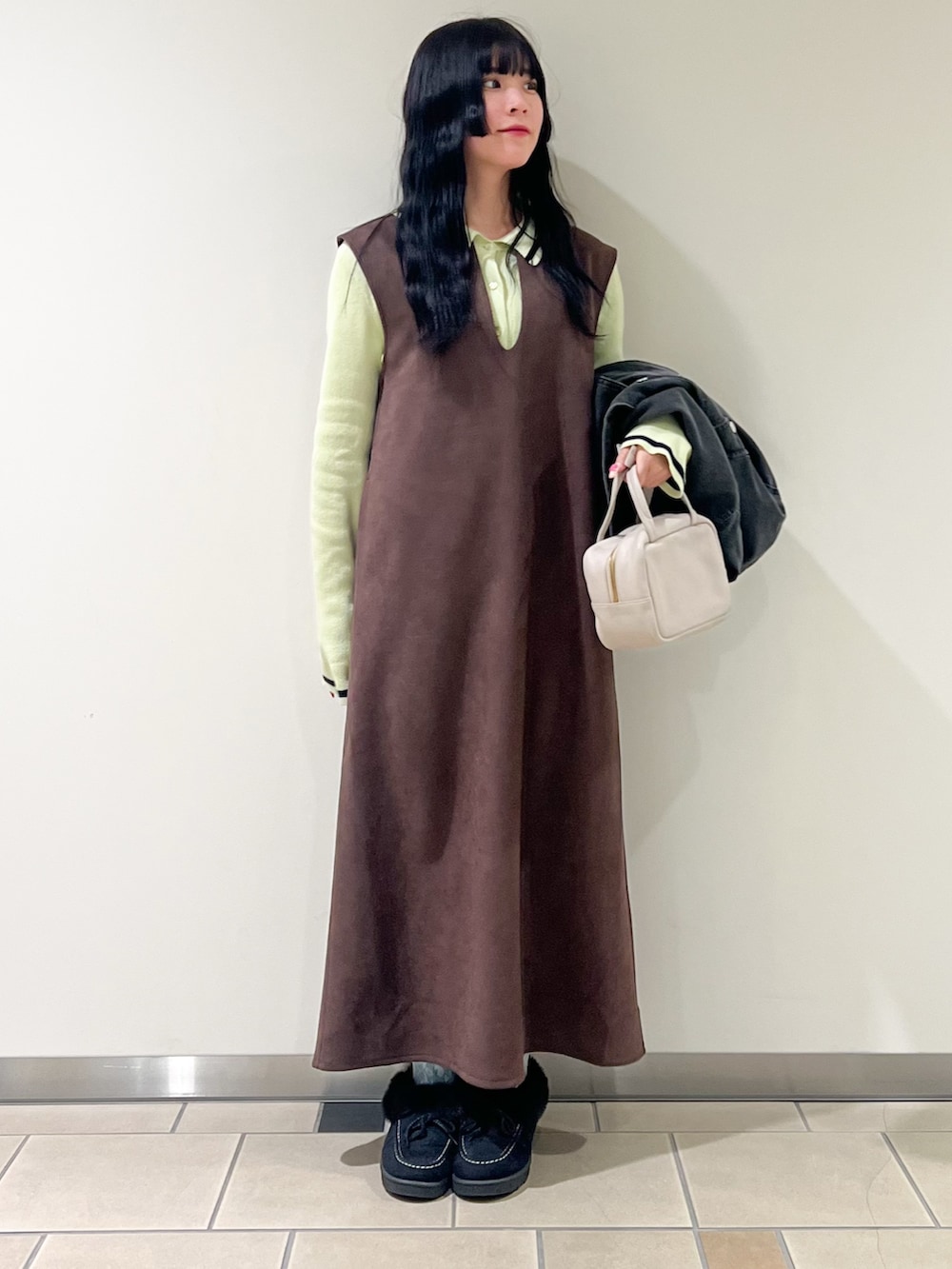 ブラウン系のジャンパースカート、グレー系のデニムジャケット、グリーン系のニット/セーターを着用したレディースの冬コーディネートの2枚目の写真