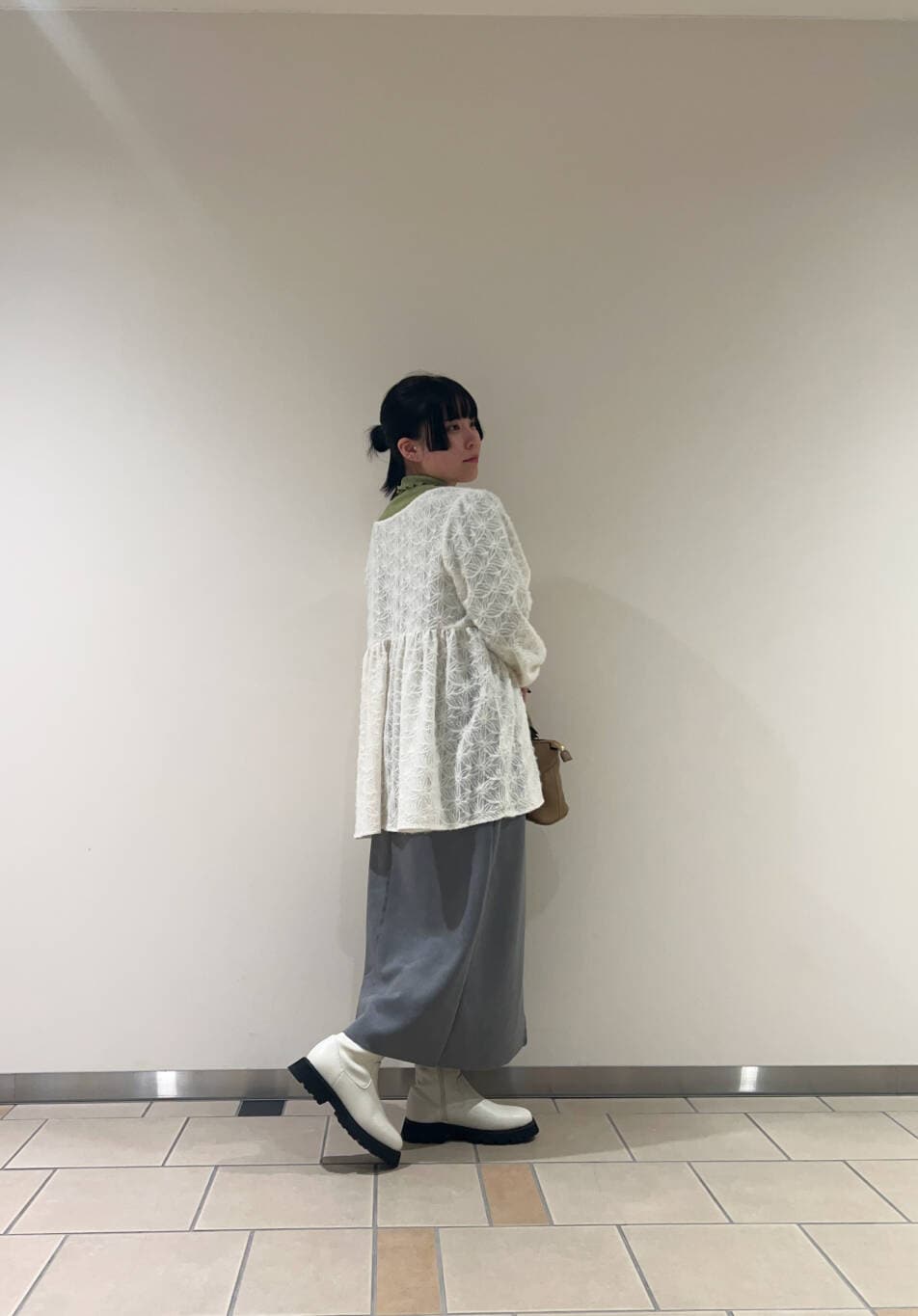 ホワイト系のブーツ、ブラウン系のボストンバッグ、グリーン系のTシャツ/カットソーを着用したレディースの冬コーディネートの2枚目の写真