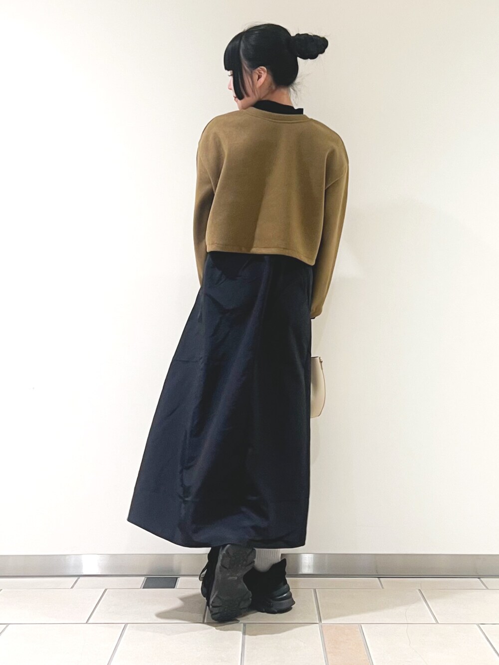 イエロー系のワンピース、ホワイト系のショルダーバッグを着用したレディースの秋コーディネートの2枚目の写真