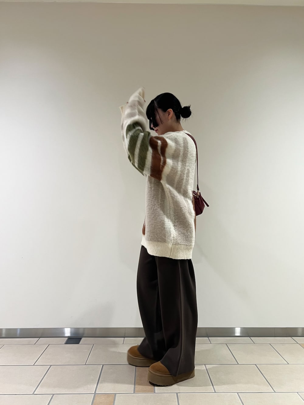 ブラウン系のその他パンツ、ベージュ系のニット/セーター、レッド系のショルダーバッグを着用したレディースの冬コーディネートの2枚目の写真