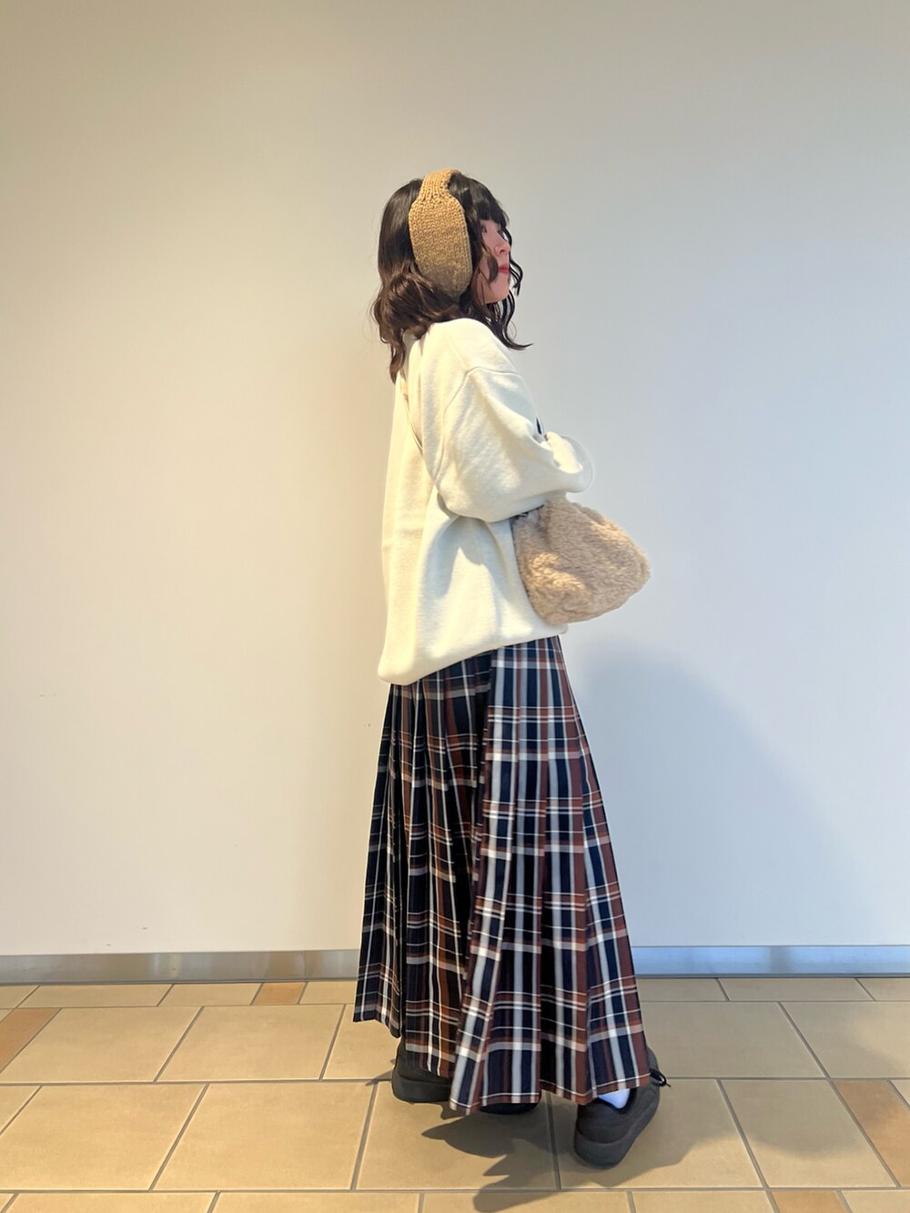 ベージュ系のショルダーバッグ、ホワイト系のニット/セーター、ブルー系のスカートを着用したレディースの秋コーディネートの2枚目の写真