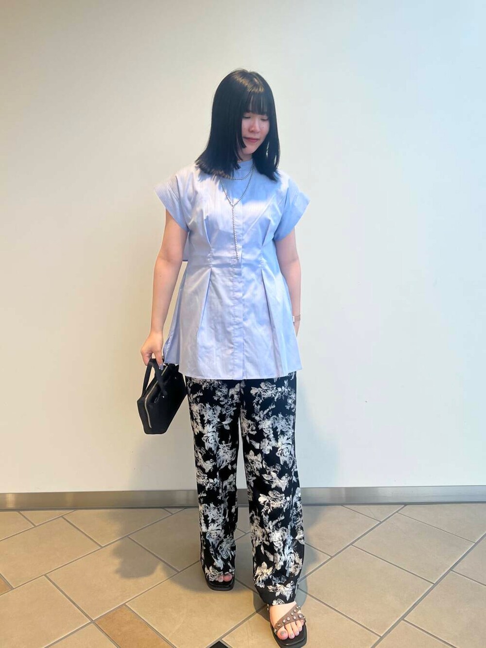 ブラック系のショルダーバッグ、ブラック系のサンダル、パープル系のシャツ/ブラウスを着用したレディースの夏コーディネートの2枚目の写真