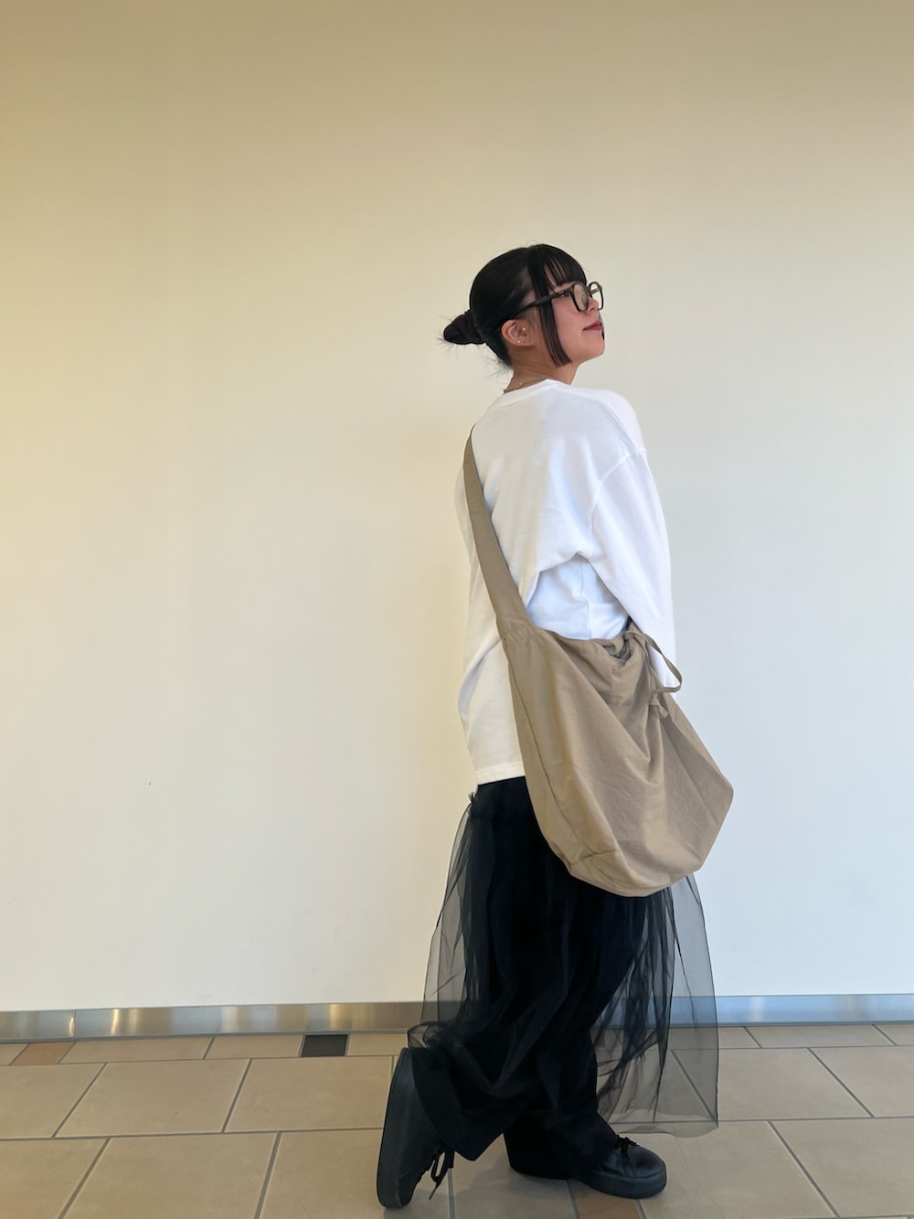 ベージュ系のショルダーバッグ、ブラック系のチノパンツ、ブラック系のワンピースを着用したレディースの秋コーディネートの2枚目の写真