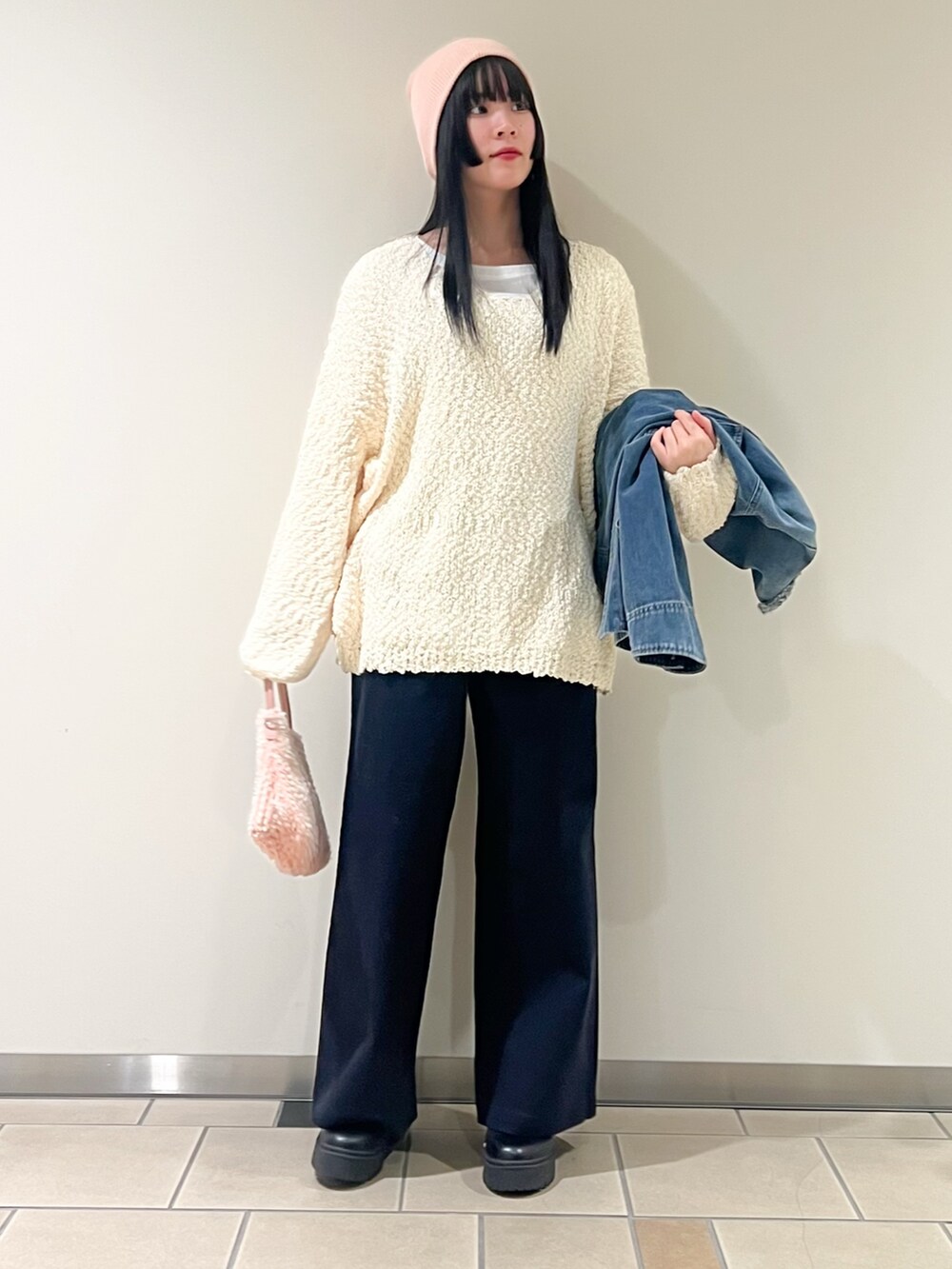 ブルー系のデニムジャケット、ホワイト系のニット/セーター、ピンク系のショルダーバッグを着用したレディースの冬コーディネートの2枚目の写真