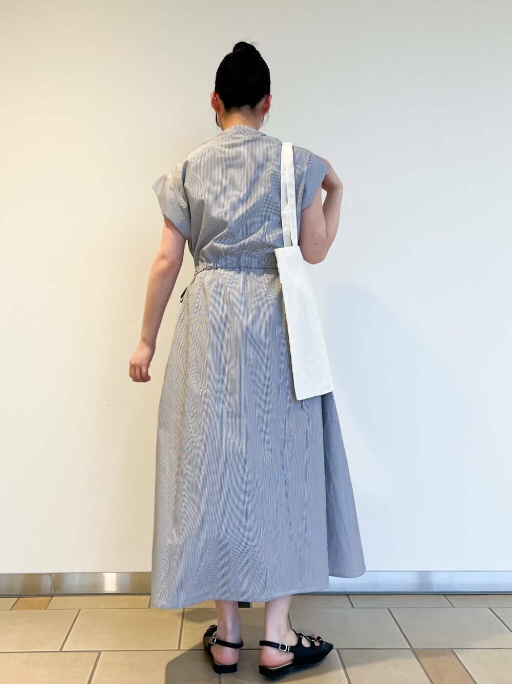 ブラック系のサンダル、ホワイト系のトートバッグ、ブルー系のワンピースを着用したレディースの夏コーディネートの2枚目の写真