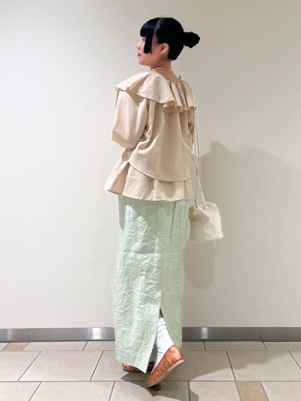 イエロー系のパンプス、グリーン系のスカート、ホワイト系のショルダーバッグを着用したレディースの春コーディネートの2枚目の写真