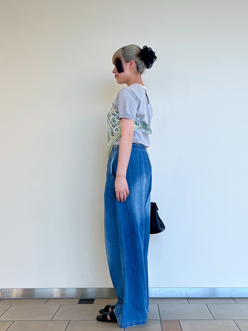 グレー系のニット/セーター、ブルー系のデニムパンツ、ブラック系のハンドバッグを着用したレディースの夏コーディネートの3枚目の写真