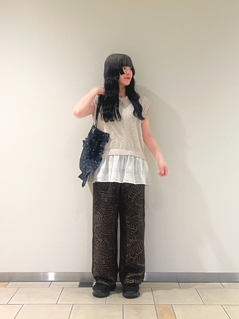 ホワイト系のニット/セーター、ブラウン系のその他パンツ、ブラック系のトートバッグを着用したレディースの夏コーディネートの3枚目の写真