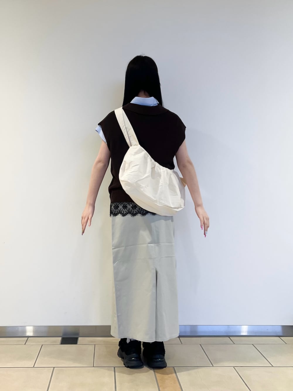 ブルー系のシャツ/ブラウス、ブラウン系のニット/セーター、ベージュ系のスカートを着用したレディースの春コーディネートの3枚目の写真