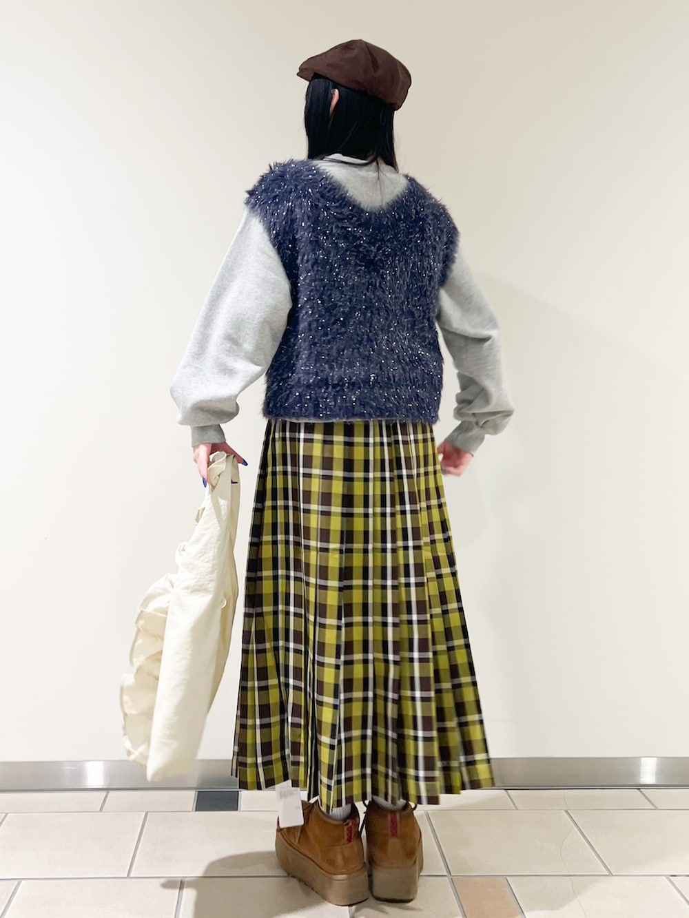 ホワイト系のトートバッグ、グリーン系のスカート、ブルー系のベストを着用したレディースの冬コーディネートの3枚目の写真