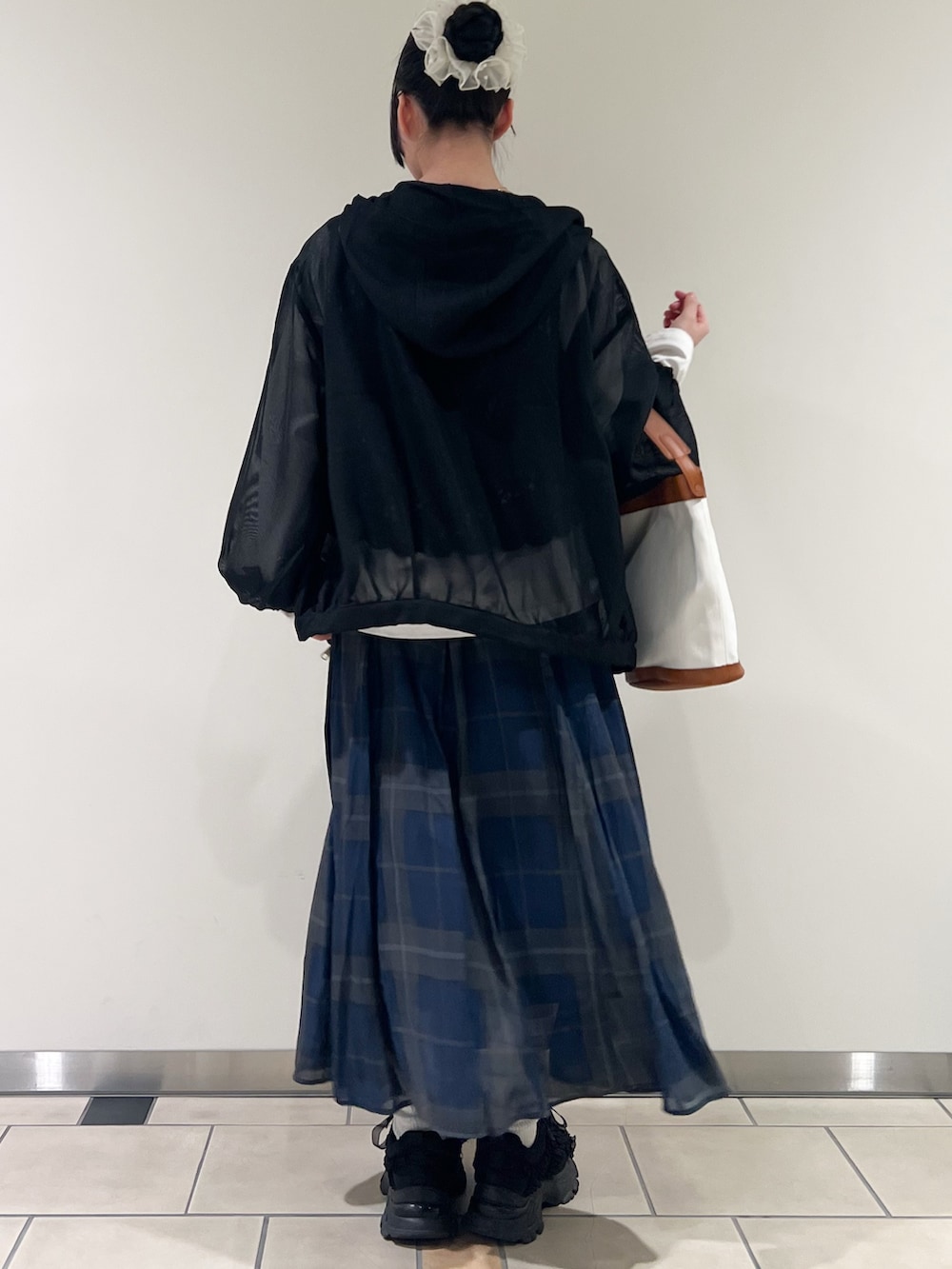 ブルー系のスカート、ブラック系のTシャツ/カットソー、ブラック系のマウンテンパーカーを着用したレディースの春コーディネートの3枚目の写真