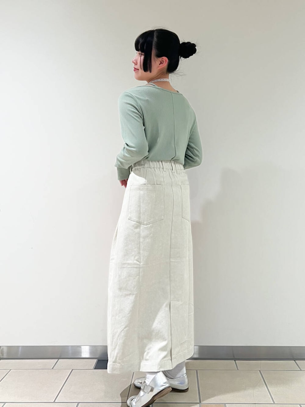 レッド系のトートバッグ、グリーン系のTシャツ/カットソー、ホワイト系のスカートを着用したレディースの春コーディネートの2枚目の写真