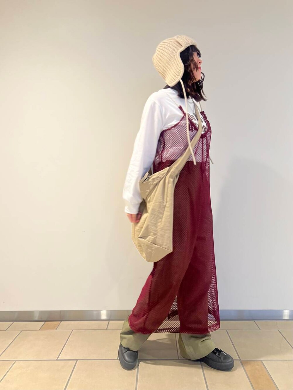 ベージュ系のショルダーバッグ、レッド系のワンピース、グリーン系のチノパンツを着用したレディースの秋コーディネートの2枚目の写真