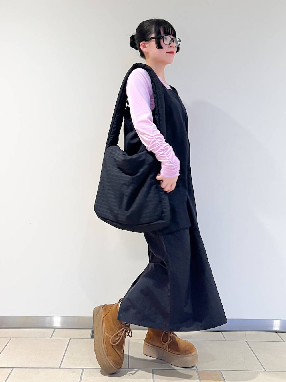 ブラック系のショルダーバッグ、ピンク系のTシャツ/カットソー、ブラック系のワンピースを着用したレディースの春コーディネートの2枚目の写真