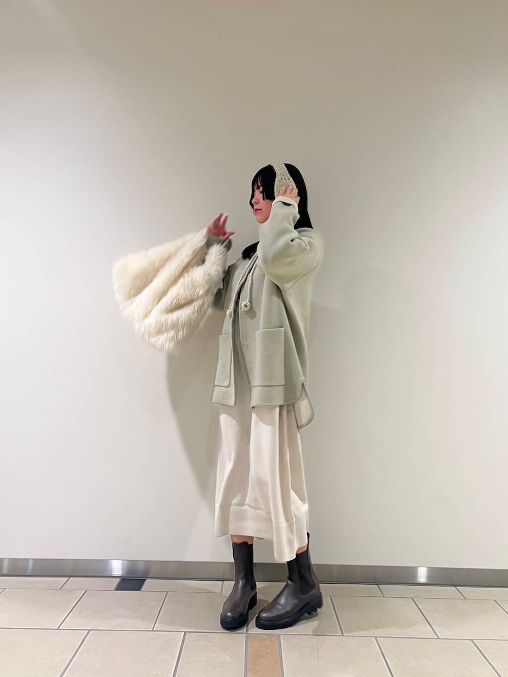 ブラウン系のブーツ、グレー系のワンピース、ホワイト系のトートバッグを着用したレディースの冬コーディネートの2枚目の写真