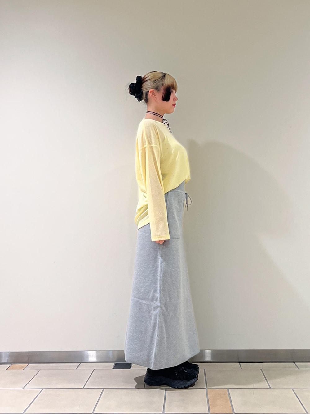 グレー系のスカート、イエロー系のTシャツ/カットソー、ブラック系のネックレスを着用したレディースの夏コーディネートの3枚目の写真