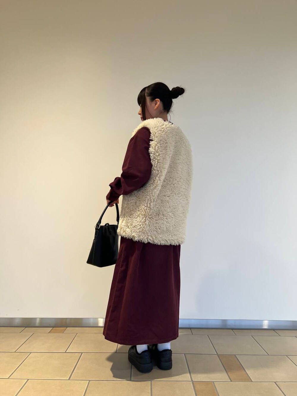 ベージュ系のベスト、レッド系のワンピース、ブラック系のハンドバッグを着用したレディースの秋コーディネートの2枚目の写真