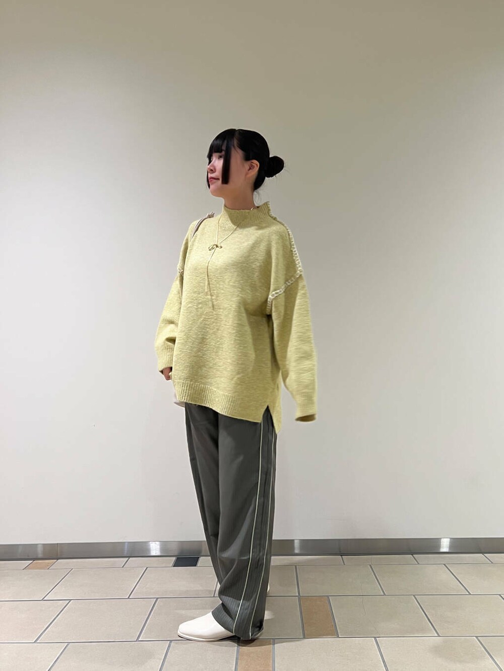 ホワイト系のブーツ、ホワイト系のショルダーバッグ、イエロー系のニット/セーターを着用したレディースの秋コーディネートの2枚目の写真