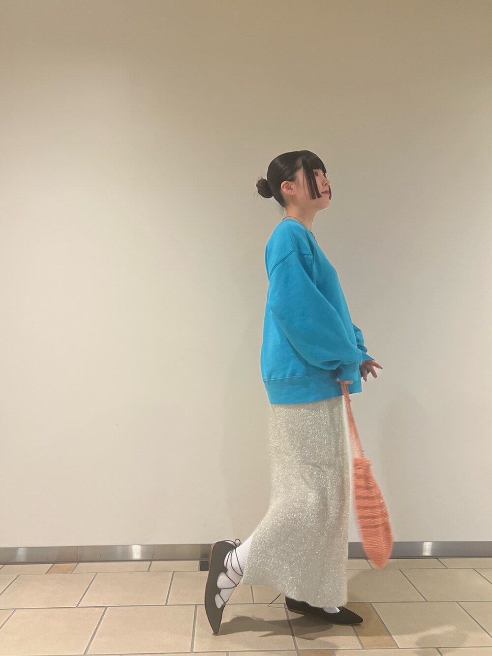 ブルー系のスウェット、ベージュ系のスカート、オレンジ系のハンドバッグを着用したレディースの秋コーディネートの3枚目の写真