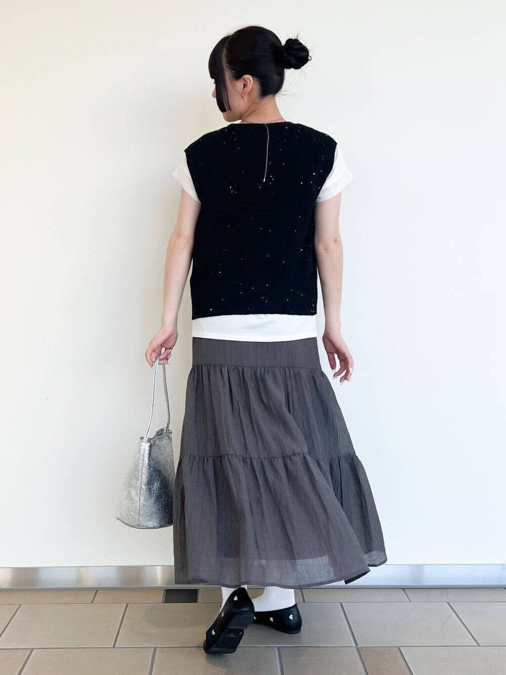 ブラック系のパンプス、シルバー系のハンドバッグ、ホワイト系のTシャツ/カットソーを着用したレディースの夏コーディネートの3枚目の写真