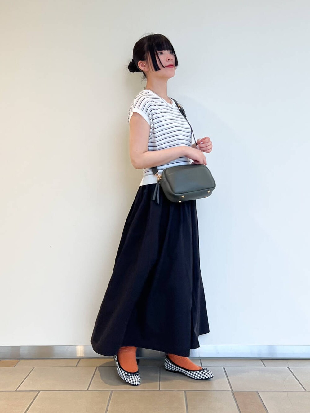 ブラック系のバレエシューズ、グリーン系のショルダーバッグ、ブラック系のワンピースを着用したレディースの夏コーディネートの2枚目の写真