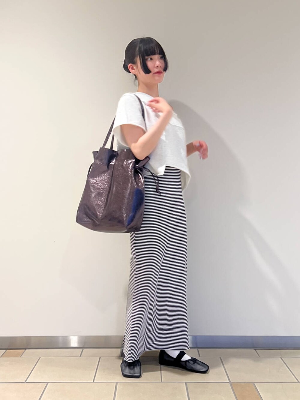 グレー系のトートバッグ、ブラック系のパンプス、ホワイト系のワンピースを着用したレディースの夏コーディネートの2枚目の写真