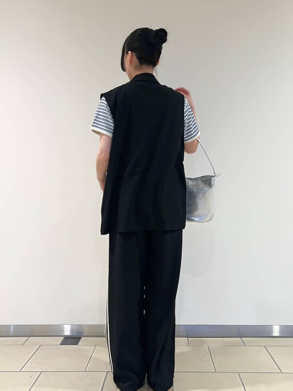 シルバー系のハンドバッグ、ブラック系のベスト、ブルー系のTシャツ/カットソーを着用したレディースの春コーディネートの3枚目の写真