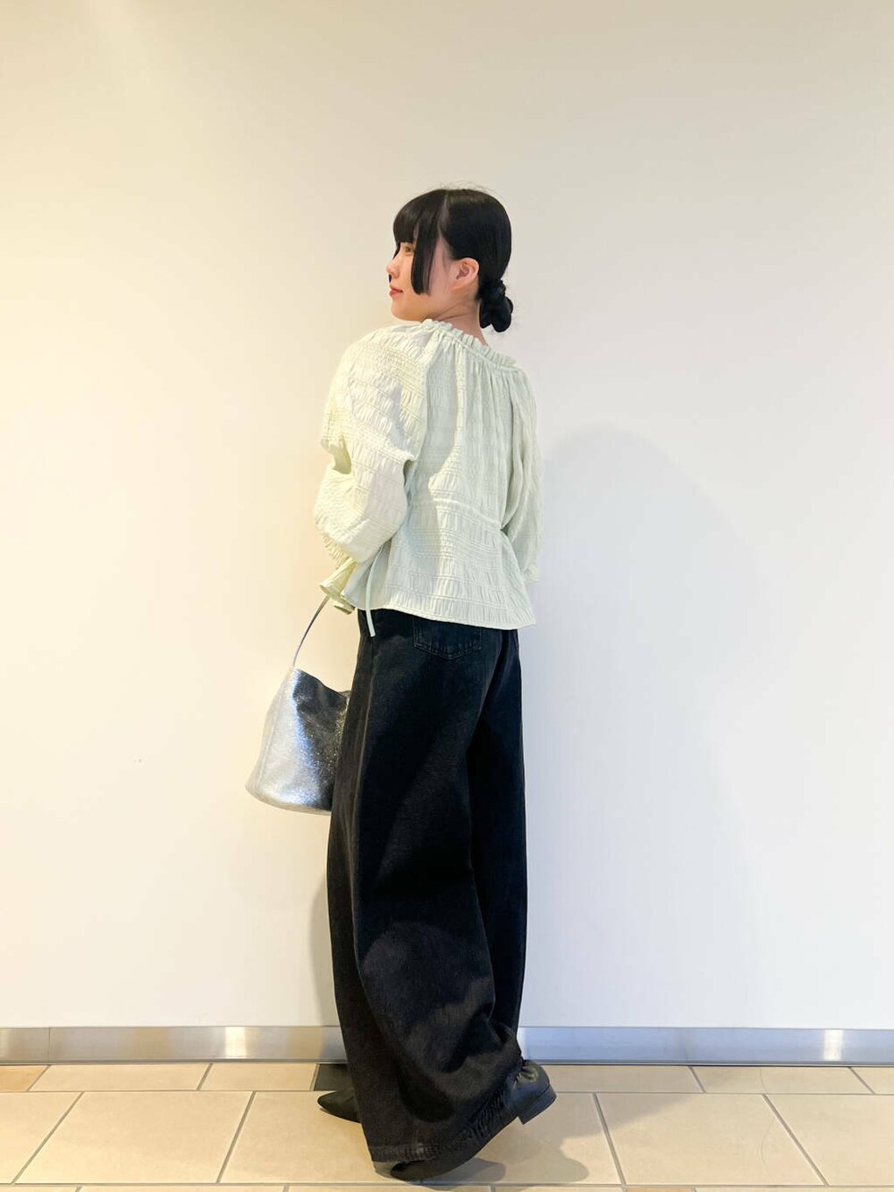 シルバー系のハンドバッグ、ブラック系のデニムパンツ、グリーン系のシャツ/ブラウスを着用したレディースの春コーディネートの2枚目の写真