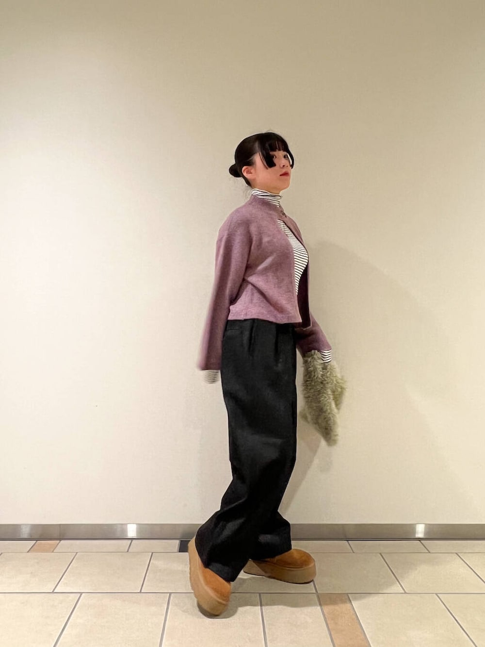 グリーン系のハンドバッグ、ブラック系のデニムパンツ、ホワイト系のTシャツ/カットソーを着用したレディースの冬コーディネートの2枚目の写真