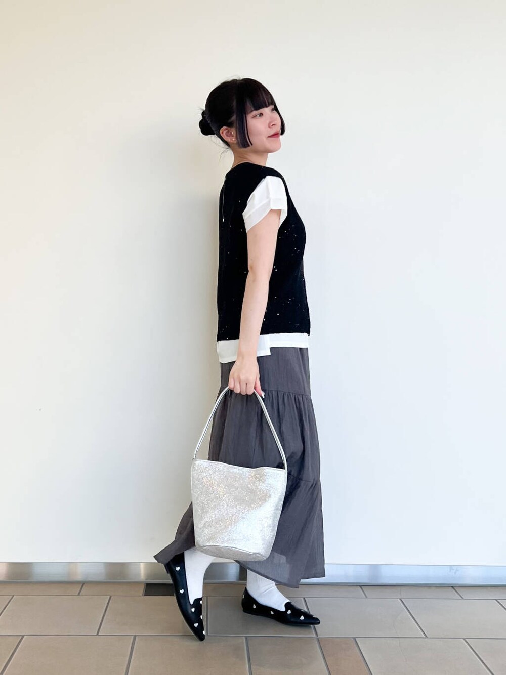 ブラック系のパンプス、シルバー系のハンドバッグ、ホワイト系のTシャツ/カットソーを着用したレディースの夏コーディネートの2枚目の写真