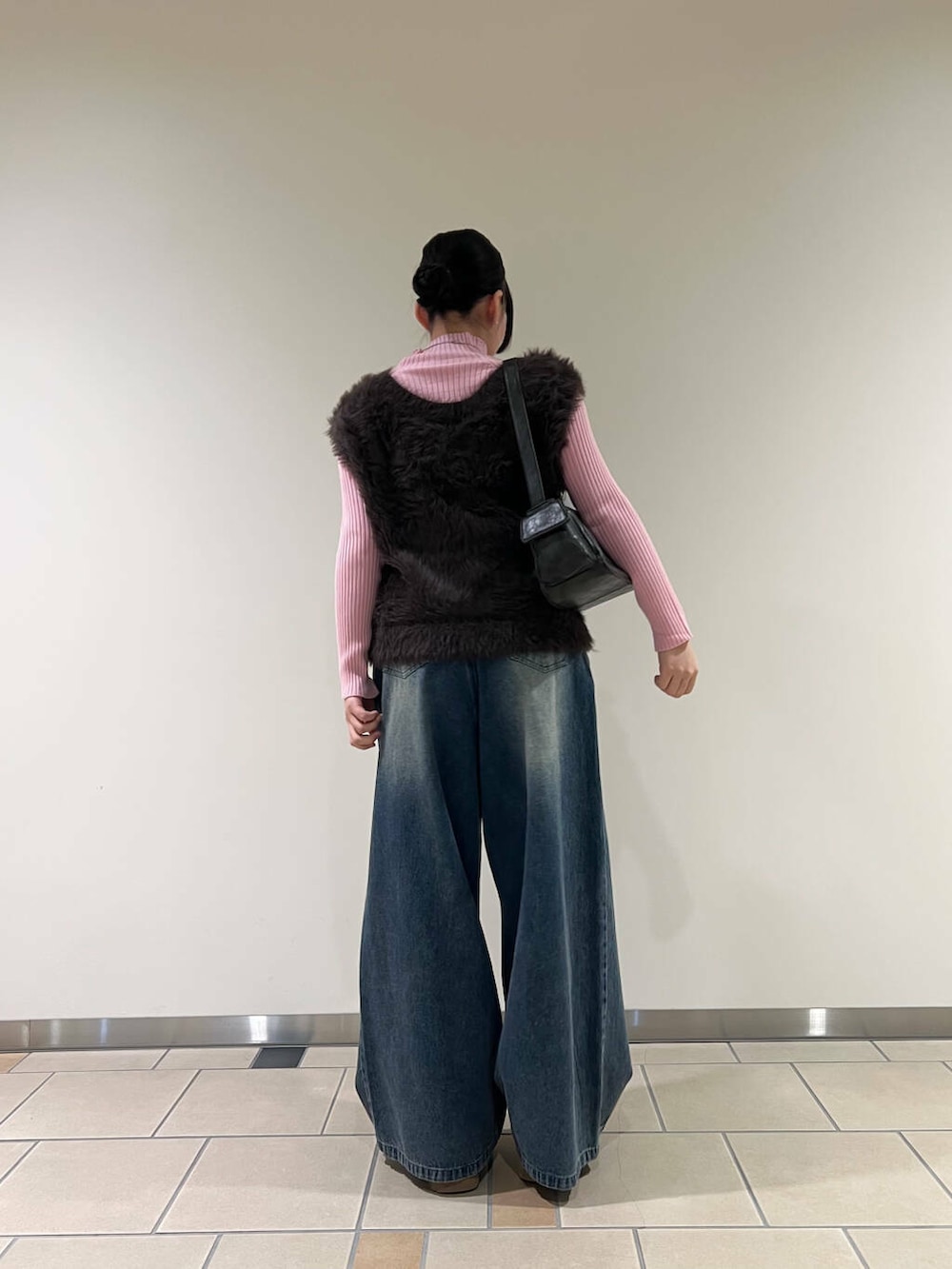 ピンク系のニット/セーター、ブラック系のハンドバッグ、ブルー系のデニムパンツを着用したレディースの冬コーディネートの3枚目の写真