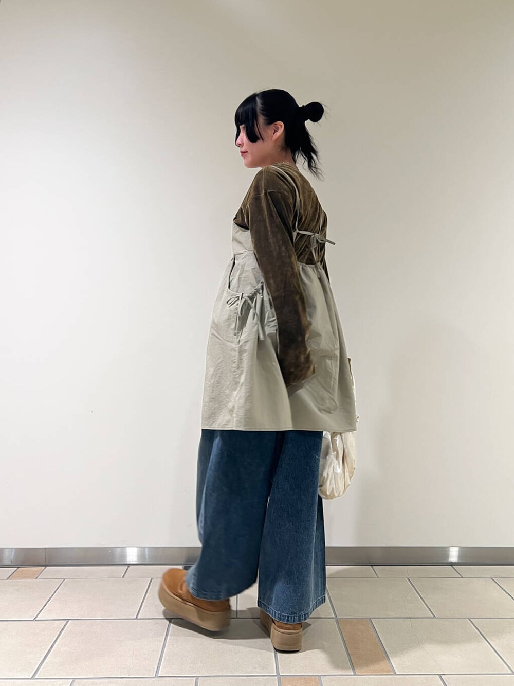 ベージュ系のハンドバッグ、ブルー系のデニムパンツ、ベージュ系のキャミソールを着用したレディースの春コーディネートの3枚目の写真