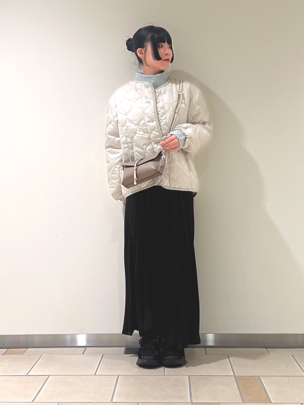 グリーン系のニット/セーター、グレー系のスカート、ホワイト系のダウンジャケット/コートを着用したレディースの秋コーディネートの2枚目の写真