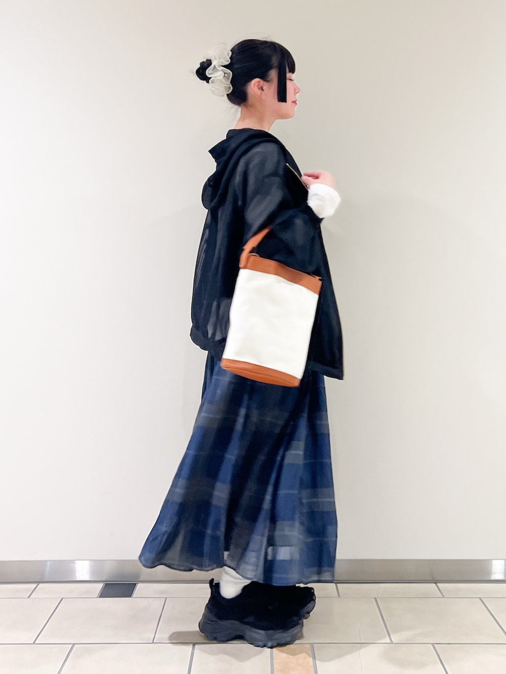 ブルー系のスカート、ブラック系のTシャツ/カットソー、ブラック系のマウンテンパーカーを着用したレディースの春コーディネートの2枚目の写真