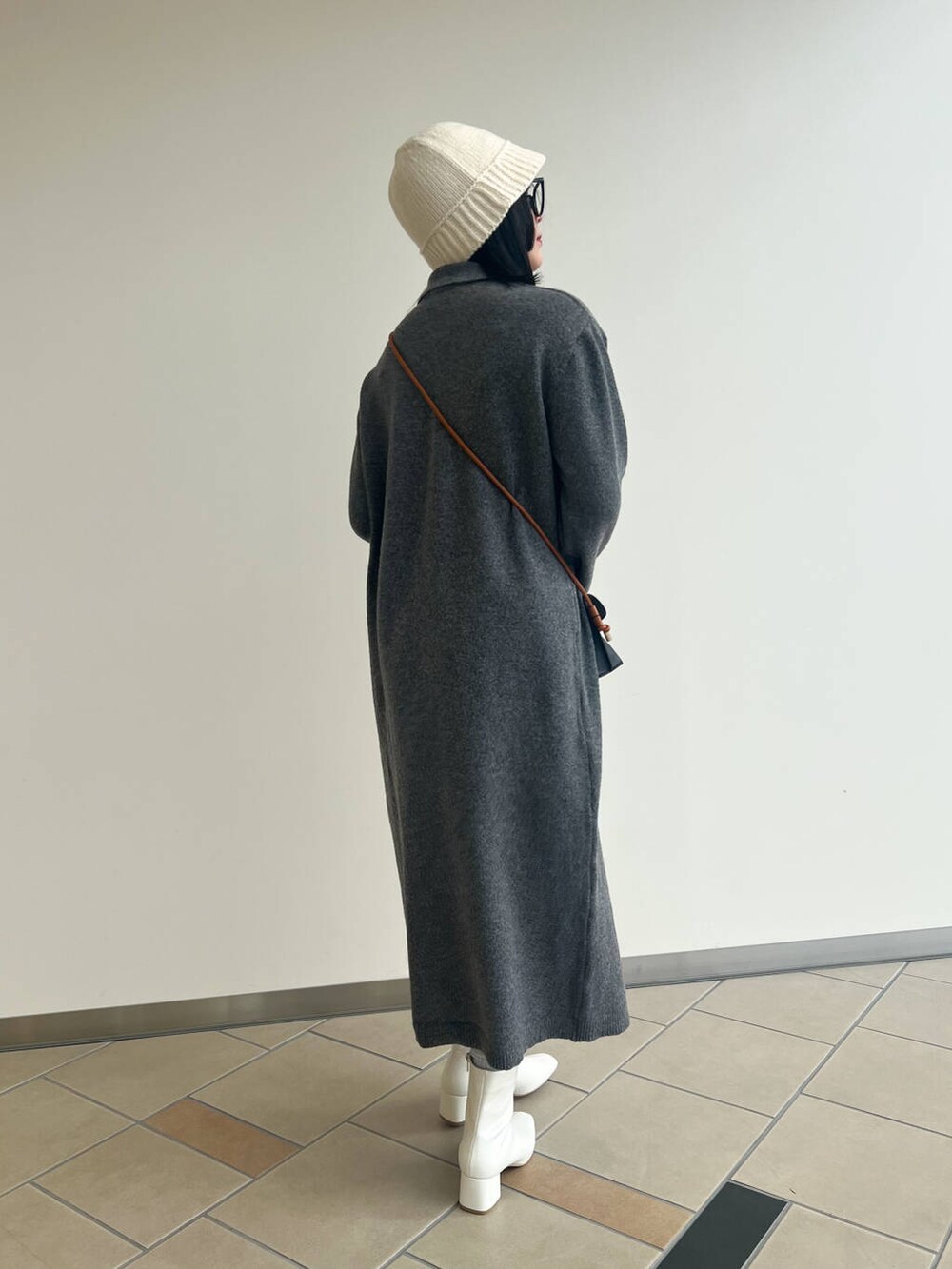 ブラック系のショルダーバッグ、ホワイト系のブーツ、グレー系のワンピースを着用したレディースの秋コーディネートの3枚目の写真